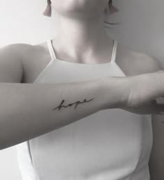 a woman with a tattoo on her arm that says hope in cursive writing