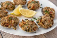 an assortment of cooked muffins on a white plate with lemon wedge and parsley