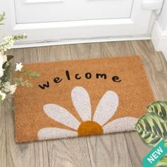 a welcome mat with the words welcome on it next to a potted plant in front of a door