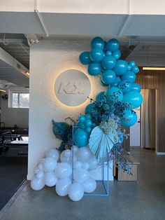 blue and white balloons are on display in an office space with a circular sign above it