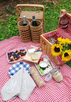 picnic food is laid out on a red and white checkered tablecloth with sunflowers