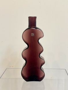 a brown vase sitting on top of a glass shelf in front of a white wall