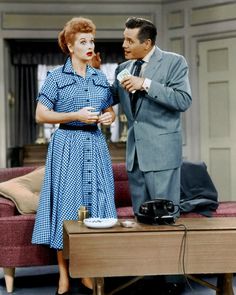 a man in a suit and tie standing next to a woman on a coffee table