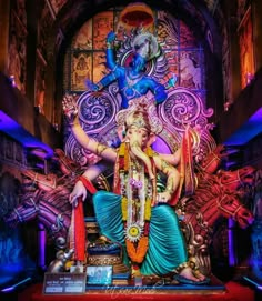 a statue of lord ganesh in front of a colorful backdrop