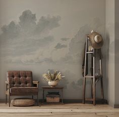 a living room with a chair and a painting on the wall behind it that has clouds in the sky