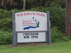 the sign for wickham park is in front of some trees