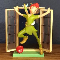 a tinkerbell figure is posed in front of an open window with the apple below