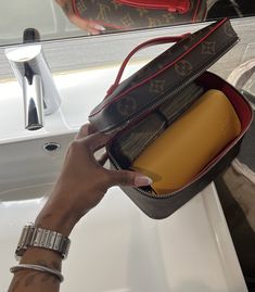 a person is holding a purse in front of a bathroom sink with a mirror behind them