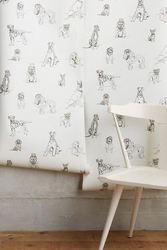 a white chair sitting next to a wall with dogs on it