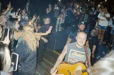 a man holding a guitar in front of a crowd