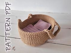 a crocheted basket with two baby blankets in it sitting on a white table