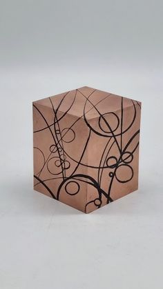 a wooden block with black and brown designs on it's sides, sitting on a white surface