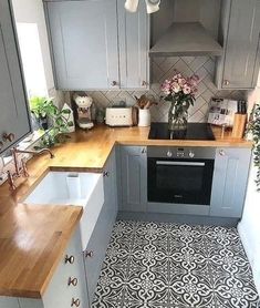 a kitchen with grey cabinets and wooden counter tops