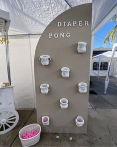 a display with cups and baskets on the wall next to a carton filled with pink balls