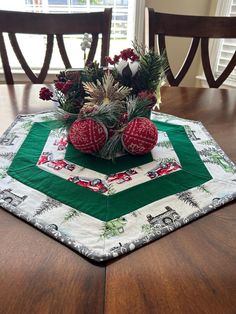 a christmas centerpiece on top of a dining room table with pine cones and ornaments