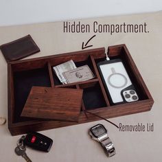 an open wooden box with keys and other items in it that include a cell phone