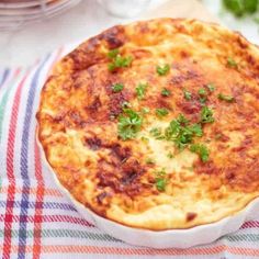 a cheesy dish is sitting on a checkered table cloth