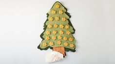 a green felt christmas tree with yellow stars on it and a white sheep standing next to it