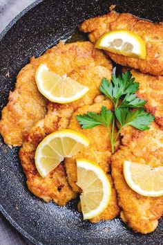 fried chicken with lemons and parsley in a skillet