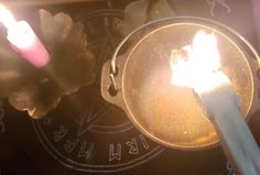 two lit candles sitting on top of a metal pan