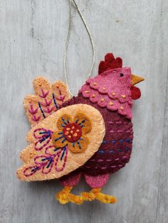 a colorful rooster ornament hanging on a wooden wall with an orange and pink decoration