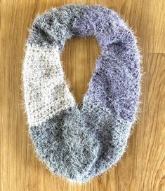 a gray and white scarf sitting on top of a wooden floor