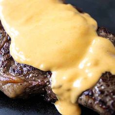 a steak covered in gravy on top of a black plate