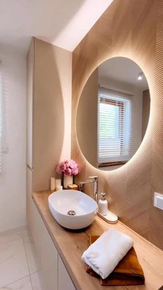 a bathroom with a round mirror above the sink and a wooden counter top next to it