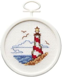 a cross stitch picture of a lighthouse with seagulls in the background