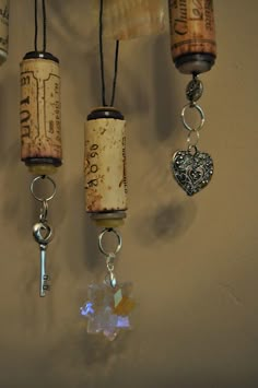 three wine corks hanging from a wall with charms attached to them and a key