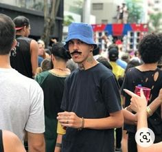 a man with a moustache on his face is surrounded by people