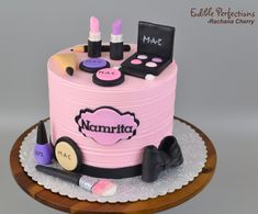 a pink cake with makeup and cosmetics on it