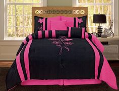 black and pink comforter set with flowers on the bed in front of windows,