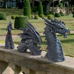 two black dragon statues sitting on top of a stone wall