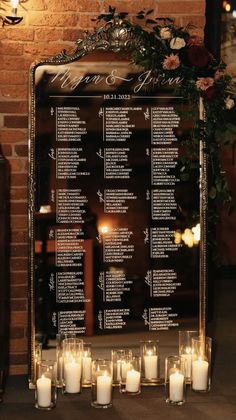 candles are lined up in front of a wedding seating chart