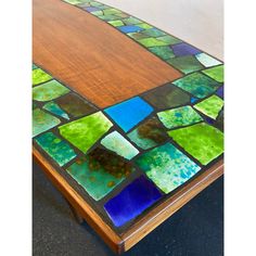 a wooden table topped with lots of different colored glass tiles on it's surface