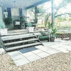 an outdoor patio with steps and potted plants on the porch, surrounded by string lights