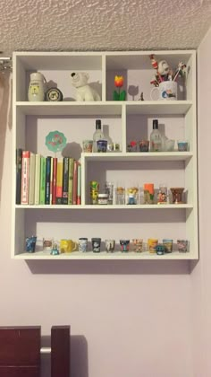 a white shelf filled with lots of books on top of a wooden dresser next to a wall