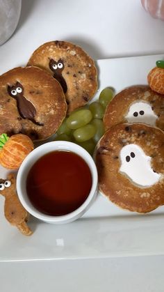 some pancakes with faces on them and grapes in the middle, sitting on a white plate