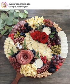 a platter filled with cheese, grapes and meats on top of a wooden table