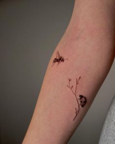 a woman's arm with a small tattoo of two bees on the back of her arm