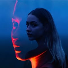 a woman standing next to a man with red light on his face in the dark