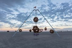 a sculpture with donuts hanging from it's sides in the middle of an empty field