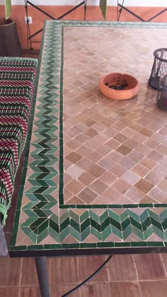 a dog bowl is sitting on top of a tiled table with a green and red pattern