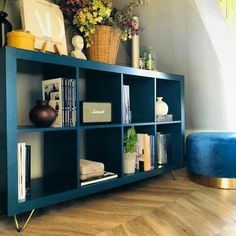 a blue shelf with books and vases on top of it in a living room