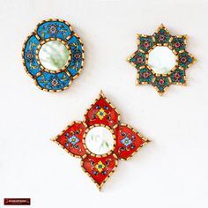 three decorative mirrors are sitting on a white surface, one is red and the other is blue