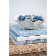 two books stacked on top of each other next to a bowl filled with blue balls