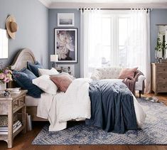 a bedroom with blue walls and white bedding in the center, along with a rug on the floor