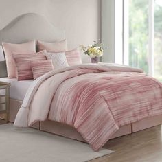 a bed with pink comforters and pillows in a room