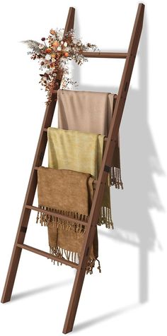 a wooden ladder with towels hanging from it's sides and flowers in the back